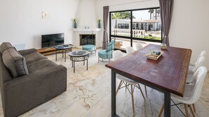 A modern living room with a sofa, TV, fireplace, and dining area with a view of the outside. - Villa Vale a Pena, for up to 40 people, near Carvoeiro.  (Carvoeiro)
