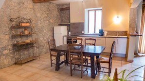 A cozy kitchen with a stone wall, wooden dining table, and chairs. - Nice confortable cottage with large pool with views in minervois  (Montbrun-Des-Corbières)