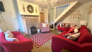 Un salon avec des canapés rouges, un tapis à motifs, une cheminée et un escalier.