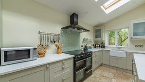Una cucina moderna con forno a microonde, fornello e forno, una rastrelliera per utensili a sospensione e una finestra vista alberi.