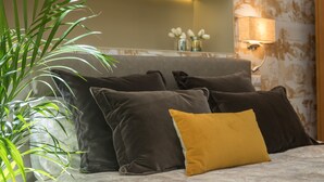 A bed with dark and mustard pillows, a potted plant, and a wall-mounted lamp. - Marvellous 3 bed / 2 bath apt near Vatican  (Roma)