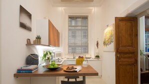 A compact kitchen with a wooden table, a microwave, a sink, and a window with blinds. - Marvellous 3 bed / 2 bath apt near Vatican  (Roma)