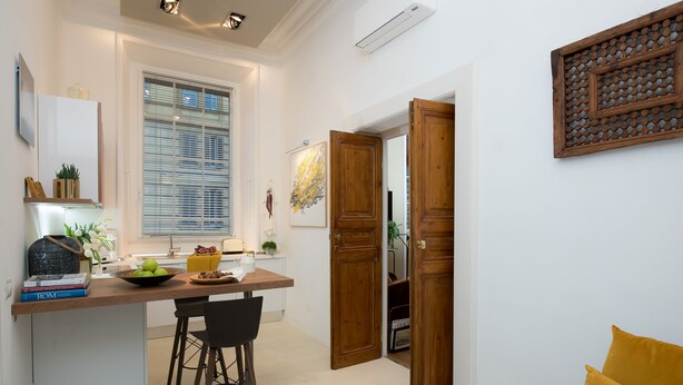 A modern kitchen with a wooden countertop, a dining area with a black chair, and a bright yellow pillow in a living space. - Marvellous 3 bed / 2 bath apt near Vatican  (Roma)
