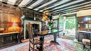 A traditional room with a fireplace, a dining table, and a chair. There is a fire exit sign visible. - Large Tudor Manor House with Private Jacuzzi & Indoor Pool, Sleeps Max 20. (Hailsham)
