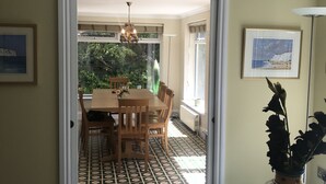 Un comedor con una mesa y sillas, piso con diseño, un florero con flores y un cuadro en la pared.