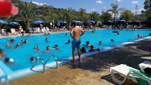 Una piscina con gente nadando y de pie junto a la piscina.