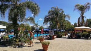 Zona de piscina con sillones, sombrillas y un restaurante llamado 'Kavani'.