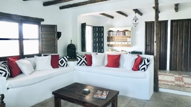 Un salón con un sofá blanco, una mesa de centro de madera y estanterías.