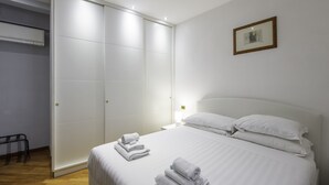 A neatly made bed with white linens and towels, a white headboard, and a framed picture on the wall. - TREVI FOUNTAIN 3 BEDROOM APARTMENT PRESTIGIOUS. (Roma)