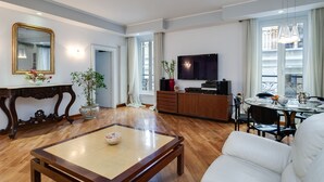 A modern living room with a sofa, a coffee table, a TV, and a dining area with a table and chairs. - TREVI FOUNTAIN 3 BEDROOM APARTMENT PRESTIGIOUS. (Roma)