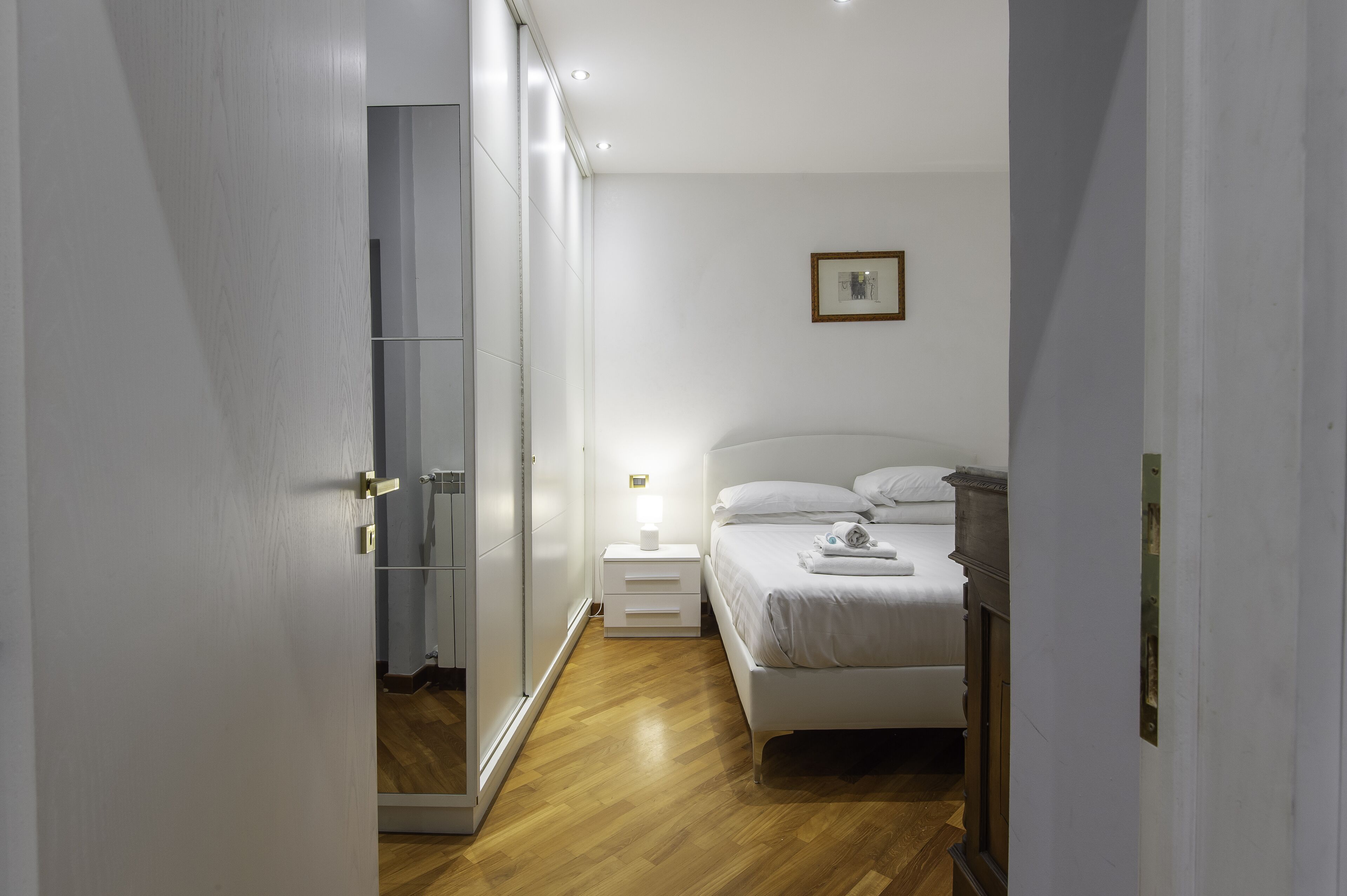 A bedroom with a bed, bedside table, and a wardrobe.