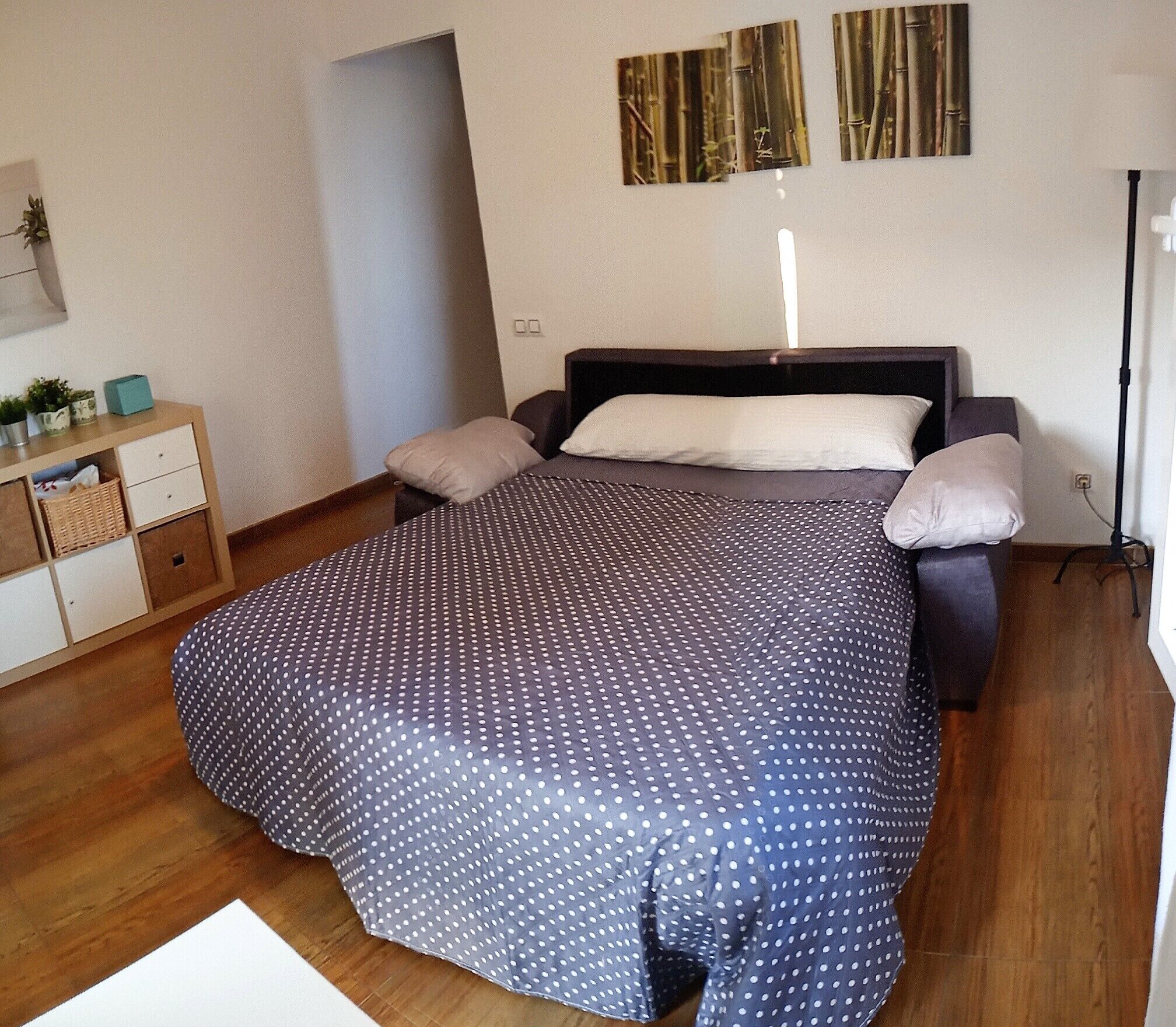 A bedroom with a bed, pillows, a nightstand, and a lamp.