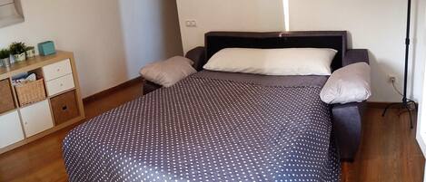 A bedroom with a bed, pillows, a nightstand, and a lamp.