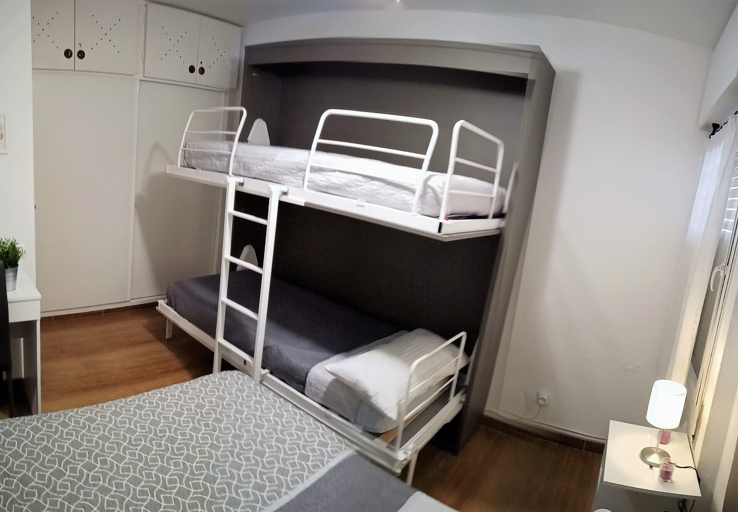 Une chambre avec un lit superposé, un bureau et une lampe.