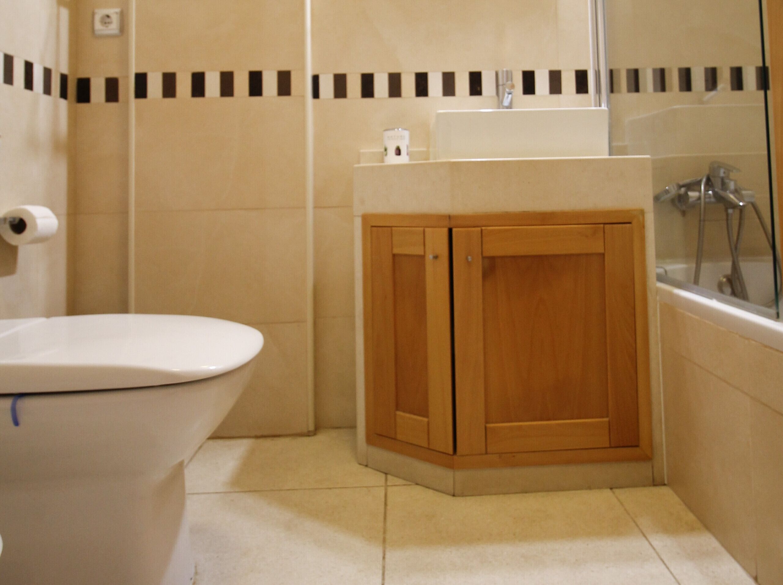 Un bagno con il water, un armadietto in legno e una vasca da bagno.