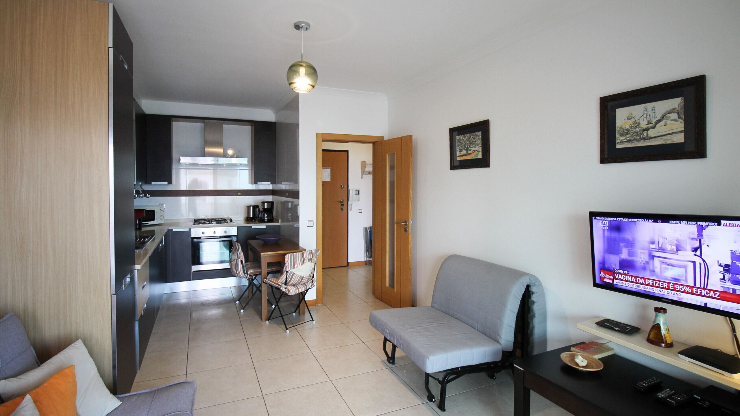 A modern apartment with a kitchen, dining area, and a living room with a TV.