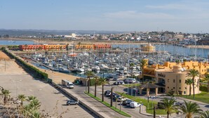 Un port de plaisance où sont amarrés de nombreux bateaux, un espace de stationnement et un bâtiment portant l’inscription « TIVOLI ».