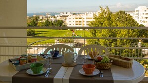 Une table sur le balcon, avec un petit-déjeuner et une vue sur la ville et un terrain de golf.