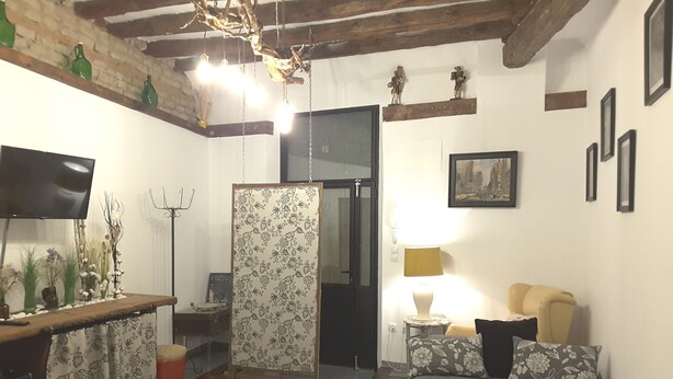 Een compacte hotelkamer met een bed, een klein zithoekje, een televisie en een kitchenette.
