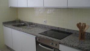 Ett kök med vita skåp, en bänkskiva i granit, en diskho i rostfritt stål och en inbyggd ugn.