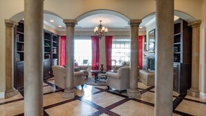 A spacious lobby with high ceilings, large columns, and a checkered floor pattern.