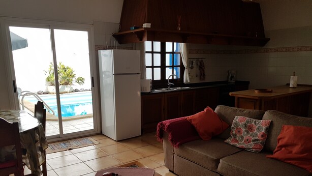 A compact living space with a kitchenette, a dining area, and a sofa with cushions. - Nice house, private pool, WIFI, near to the beach. (Caleta de Famara)