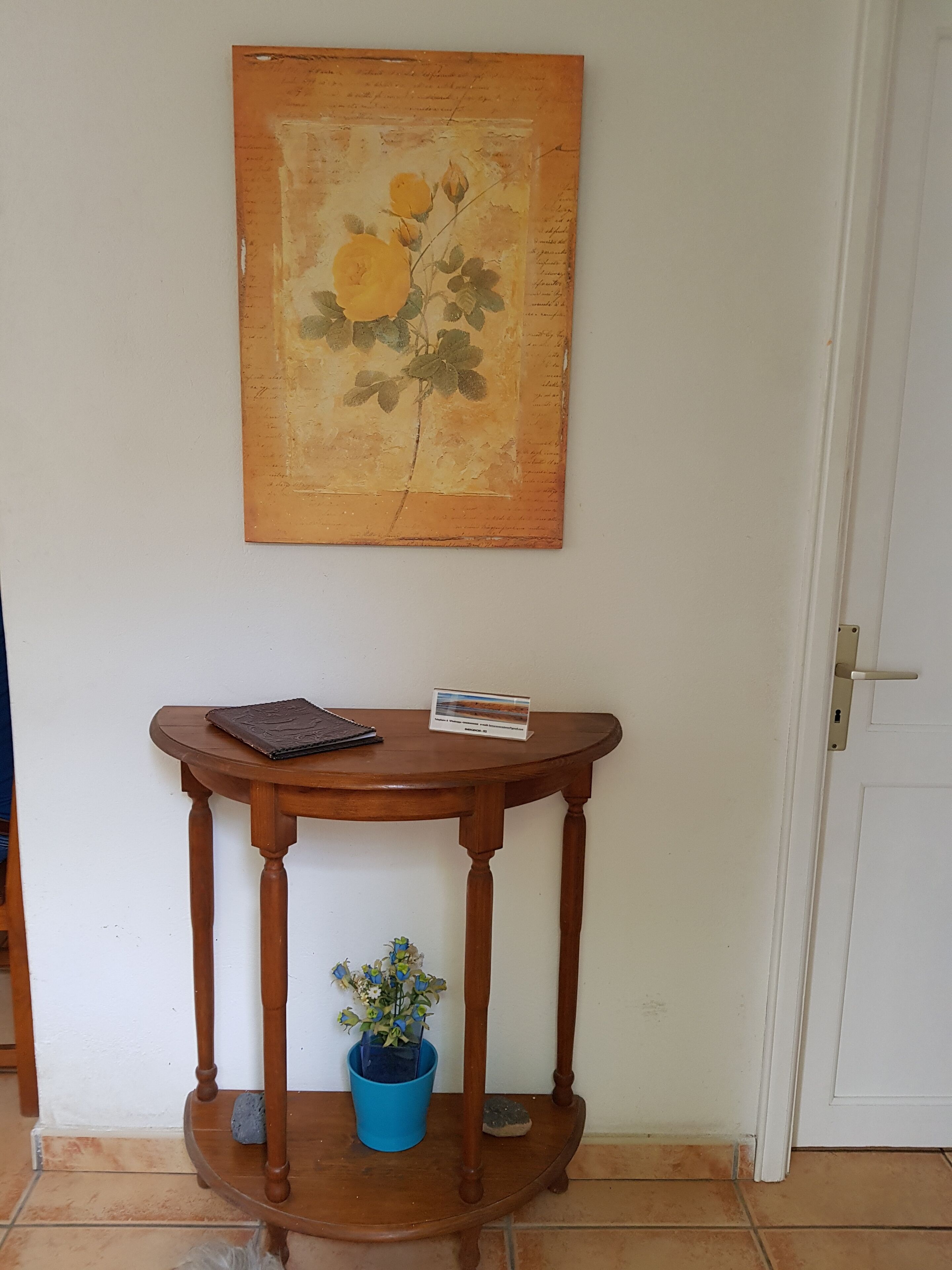 A wooden console table with a small potted plant and a sign.