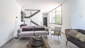 Una sala de estar moderna con un sofá, una silla, una mesa de centro y una escalera.