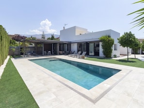 A modern house with a swimming pool, outdoor seating, and a covered patio.