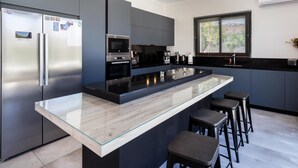 Una cocina moderna con una isla central, electrodomésticos de acero inoxidable y un ventanal amplio.