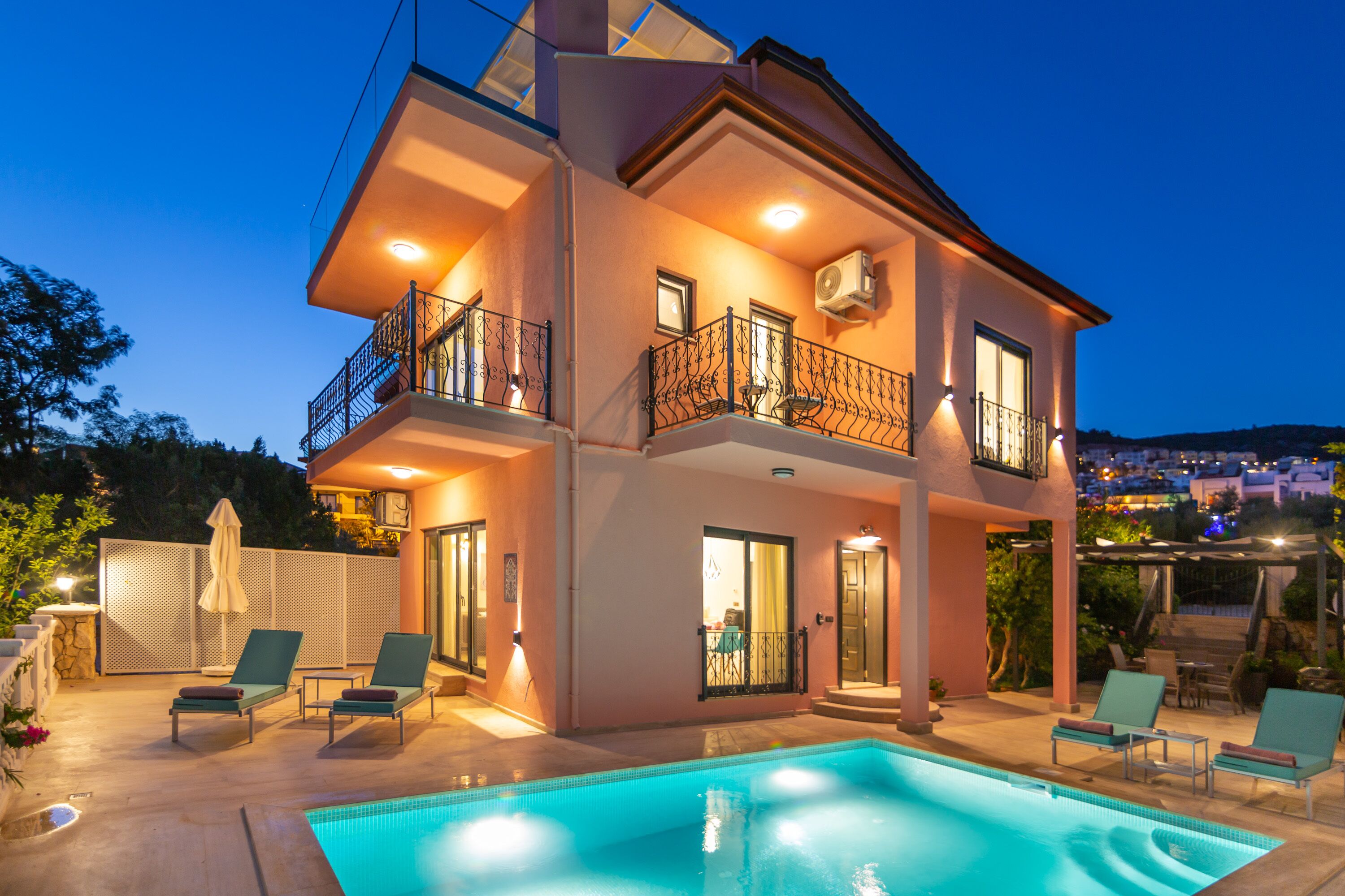 Una casa de dos pisos con piscina, balcones y mobiliario exterior.
