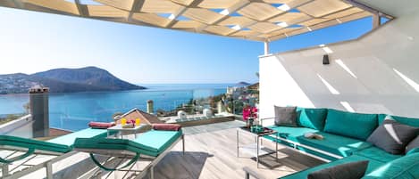 A rooftop terrace with a view of the sea, a green sofa, and a massage table.