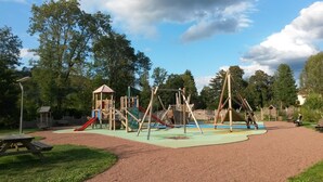 A playground with various play structures, including slides and swings, surrounded by trees and benches. - Beautiful mansion for 10 people (Le Val-D'ajol)