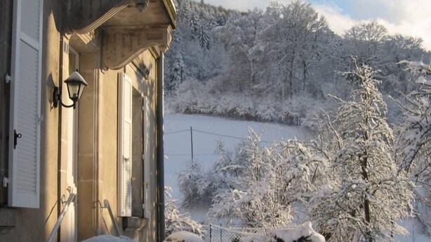 A snow-covered landscape with a house featuring a traditional design, a fence, and snow-laden trees. - Beautiful mansion for 10 people (Le Val-D'ajol)