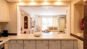 A modern kitchen with a central island, a dining area with a sofa and chairs, and a view into the living room. - Encosta do Lago, two suits Finest Apartment with Private Pool and garden. (Almancil)