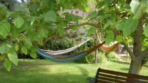 A hammock tied between trees, a wooden bench with a cushion, and a grassy area. - Country Cottage / Gite - SCHERWILLER (Scherwiller)