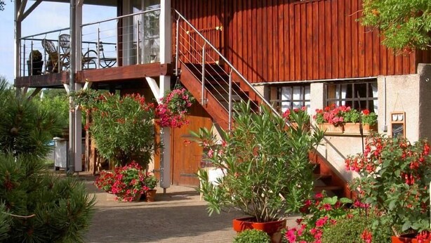 A rustic wooden building with a covered porch and a staircase leading to a second floor. - Country Cottage / Gite - SCHERWILLER (Scherwiller)