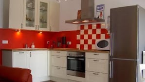 A compact kitchen with white cabinets, a built-in oven, and a stainless steel refrigerator. - Country Cottage / Gite - SCHERWILLER (Scherwiller)