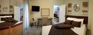 Quarto de hotel com duas camas, uma escrivaninha, uma cadeira, televisão e obras de arte nas paredes.