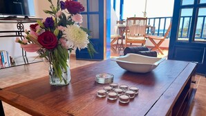 A wooden table with a vase of flowers, a bowl, and several small glass containers.