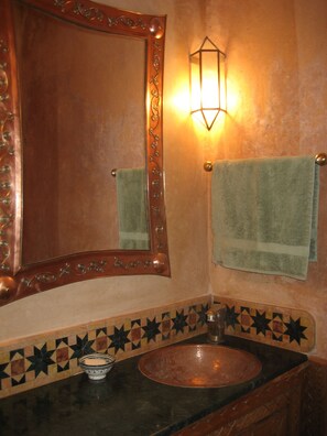 A bathroom with a copper sink, a decorative mirror, and a wall-mounted light fixture. - Jewel of a private home all to yourselves in the heart of the Old City (Marrakech)