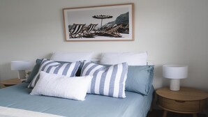 Un dormitorio con una cama, almohadas a rayas y un cuadro en la pared.