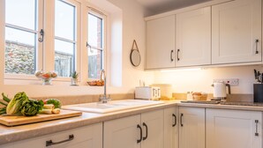 Une cuisine moderne avec des meubles blancs, un évier et une fenêtre donnant sur l’extérieur.
