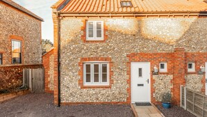 Une petite maison de campagne en pierre et en briques, avec un toit en tuiles, une porte en bois et un petit jardin.