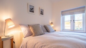 Une chambre à coucher avec un lit, deux lampes fixées au mur et deux tableaux encadrés accrochés au mur.
