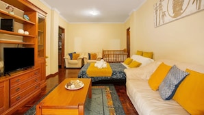 A living room with a sofa, a TV, a wooden cabinet, and a dining table. - Madeira Funchal Gardens (Funchal)