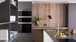 A modern kitchen with a built-in oven, a sink, and a wooden countertop.