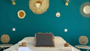A bedroom with a teal wall, a bed with white linens, a dark gray pillow, and two round woven chairs. - House / Villa - VILLANOVA (Villanova)