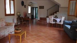 A living room with a sofa, a coffee table with a flower arrangement, a dining table with chairs, and a staircase leading to an upper floor. - Villa Raffaela - Stately home, independent, quiet, sunny, ideal for a relaxing holiday (Ercolano)