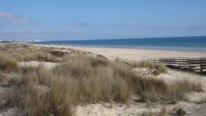 A beach with a wooden boardwalk leading to the shore.